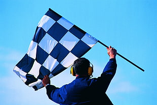 man holding a checked flag with earmuffs
