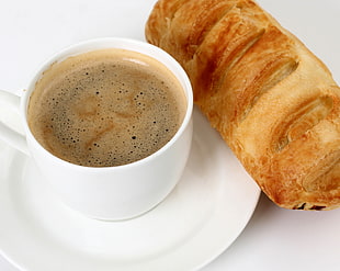white ceramic cup filled with coffee near french bread