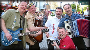 five men holding assorted musical instruments