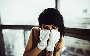 shallow focus photography of woman covering her face with pair of white gloves