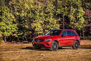 red Mercedes Benz sport utility vehicle beside green leaf trees