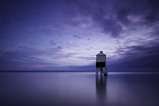 white and black wooden lighthouse near beach under gray sky, burnham