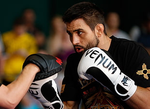 man wearing black shirt and white Venum boxing gloves