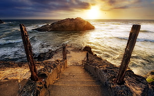 stair remains descending to sea at sunset