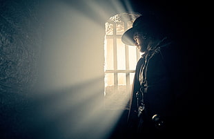 man wearing cowboy hat inside cell standing and looking outside grilled window