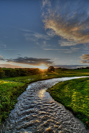 curved flowing river between grass open field, rays