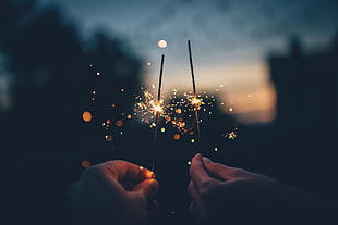 person holding sparkler firework at nightime