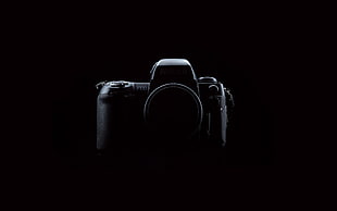 black DSLR camera in dark surface