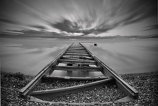 grayscale view of dock on body of water