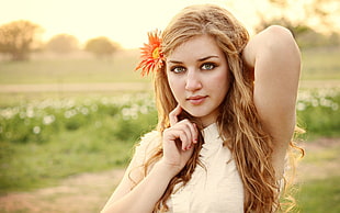 woman in white sleeveless top with orange flower in her ear during daytime