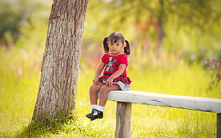 girl wearing pink floral short sitting on white wooden bench