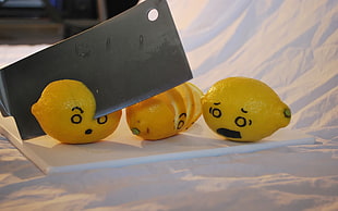 three lemons on white cutting board