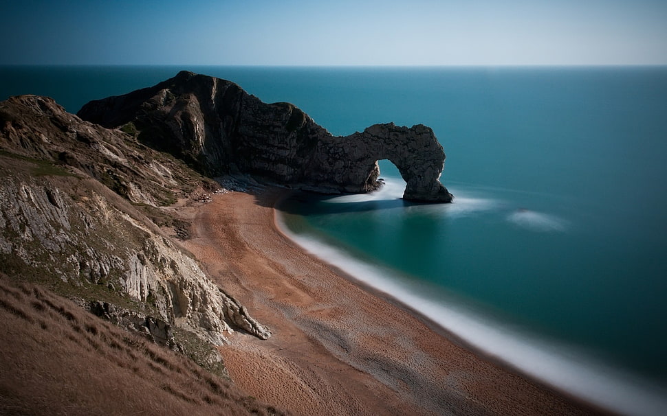 aerial photography of brown landscape near blue body of water during daytime HD wallpaper