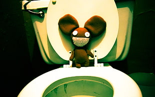 brown rodent plush toy on top of white water closet