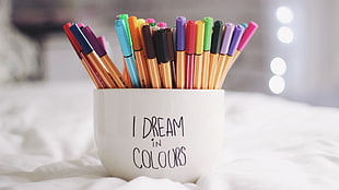 white ceramic cup with assorted color pens