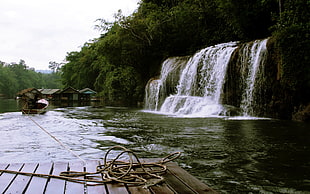 brown wooden boat in river near waterfalls