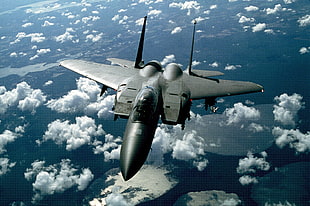 bird's eye view of black fighter jet surrounded by white clouds during daytime