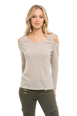 photo of woman in gray cold-shoulder shirt and green fitted jeans smiling