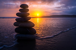 pile of stone at seashore during golden hour HD wallpaper