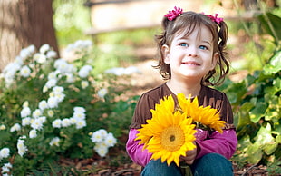 smiling girl in brown shirt holding sunflowers