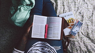 man holding book with pink pen