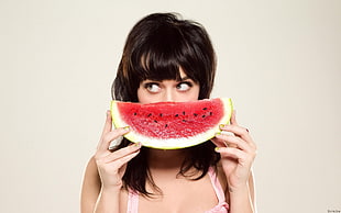 woman holding sliced of watermelon