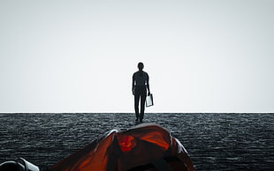 man near body of water under gray skies HD wallpaper