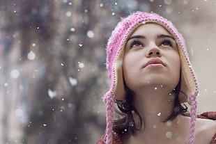 woman wearing pink knitted hat taking selfie during snow