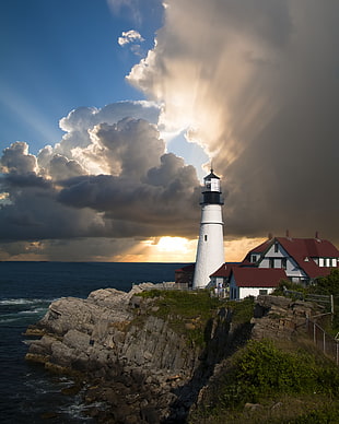 photo of white lighthouse tower with houses in the hill near ocean HD wallpaper