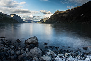 gray stones and calm body of water during daytime, gjende