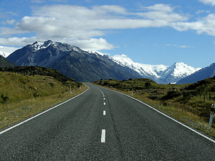 gray asphalt road surrounded by mountains during daytime