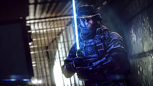 man wearing tactical gear holding blue lightsaber wallpaper