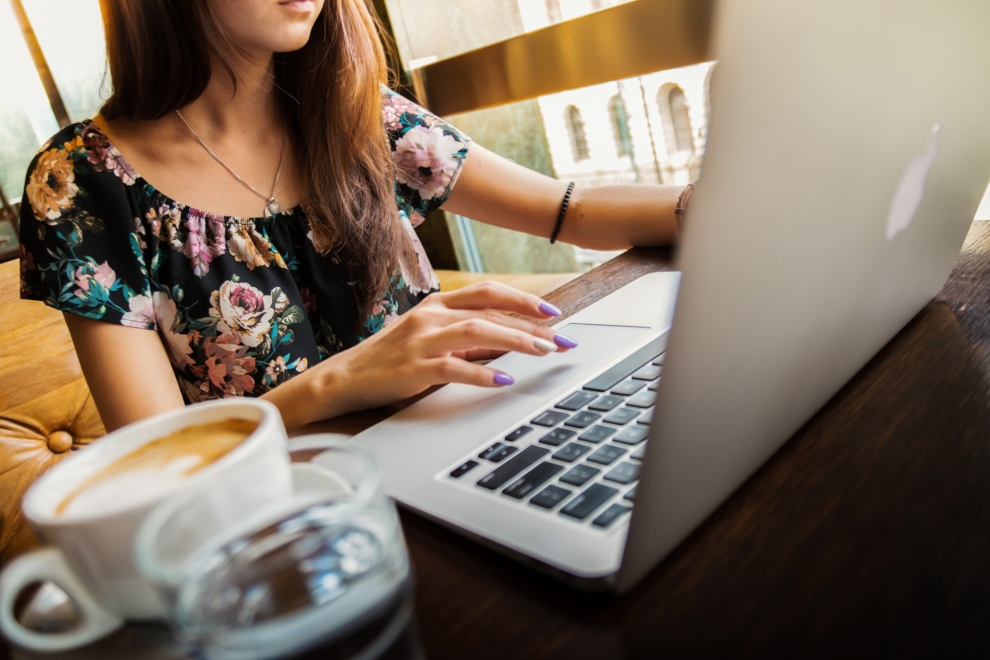 woman wearing black and pink floral print scoop-neck blouse using MacBook Air