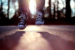 pair of black-and-white Converse All-Star low-tops, jumping, shoes, sunlight, legs