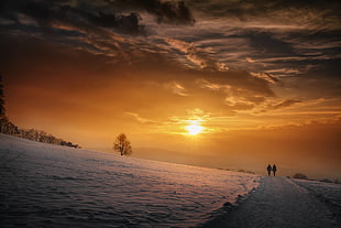 photo of two person walking during sunset