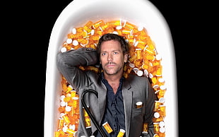 Doctor House lying down on tub of medicine containers