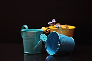 three yellow, blue, and teal watering can and bucket