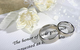 couples silver wedding ring placed on white invitation card HD wallpaper