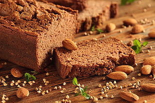 almonds near bread slice on brown wooden surface