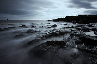 grayscale photo of misty rocky shore