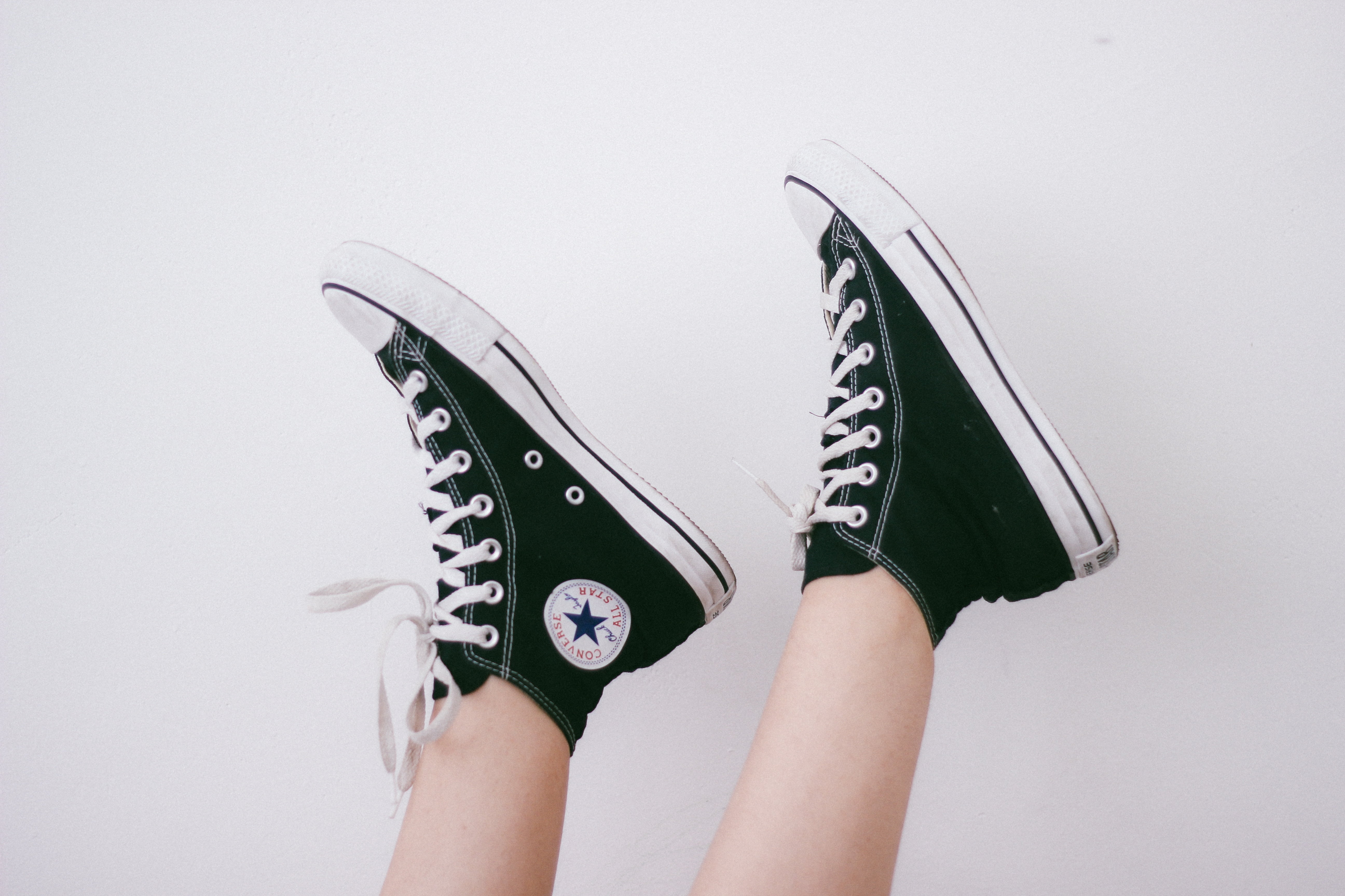 pair person wearing black Converse high-top Chuck Taylor