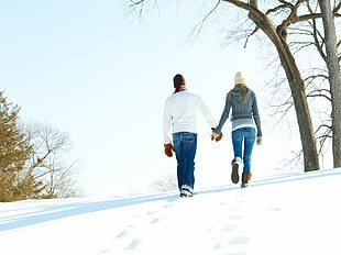 man and woman holding hands while walking on snow field HD wallpaper