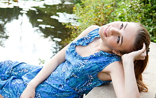 woman in blue sleeveless dress sitting near body of water during daytime