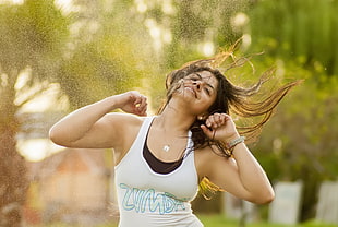 shallow focus photography of woman in white and blue zumba print tank top doing zumba dance during daytime