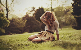 woman wearing white and brown midi dress sitting on green grass