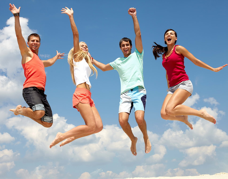 two men and two women jumped under clear blue sky during daytime HD wallpaper