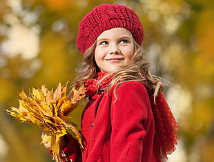 girl holding maple leaf during daytime