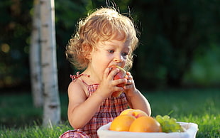 selective focus photography of girl eating apple fruit