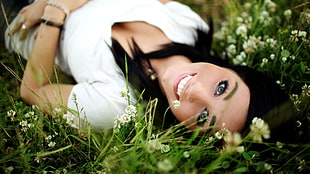 woman in white v-neck t-shirt lying on grass field in tilt shift photography