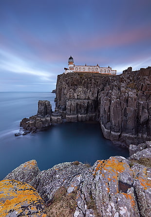 gamma photography of white and brown lighthouse on peak of rocky mountain during daytime, neist point, skye, scotland